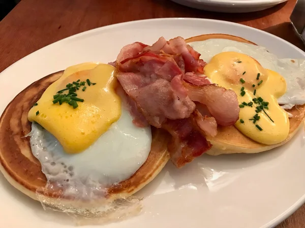 Salted Pancakes with Hollandaise Suace, Eggs and Crispy Bacon for Breakfast. Salty Organic Fast Food.