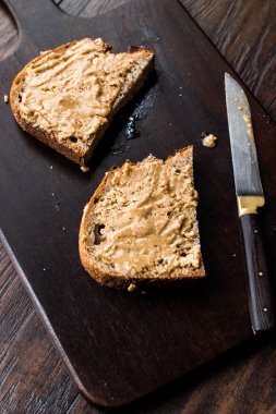 Fıstık ezmeli ekmek ve ahşap tahta üzerinde bıçak. Organik gıda.