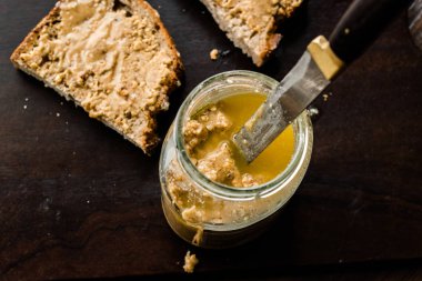 Ekmek ve ahşap yüzey üzerinde bıçak ile krem fıstık ezmesi kavanozu kahvaltı organik gıda için.