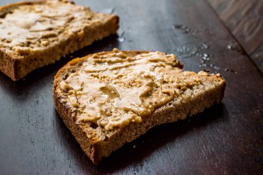 Ahşap tahta üzerinde ekmek ile krem fıstık ezmesi. Kahvaltı için organik gıda.