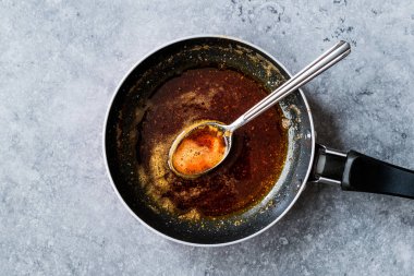 Kızartma ile kırmızı sosu hazırlarken eritilmiş tereyağı ve baharat Pan / yemek tarifi kaşıkla. Ev yapımı tarifi