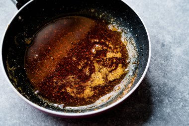 Kızartma ile kırmızı sosu hazırlarken eritilmiş tereyağı ve baharat Pan / yemek tarifi. Ev yapımı organik gıda.