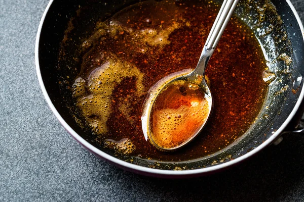 Kızartma ile kırmızı sosu hazırlarken eritilmiş tereyağı ve baharat Pan / yemek tarifi kaşıkla. Ev yapımı tarifi