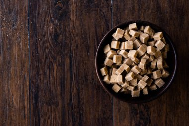 Ham organik kahverengi şeker küpleri içinde ahşap kase yemeye hazır. Gıda ürünleri.