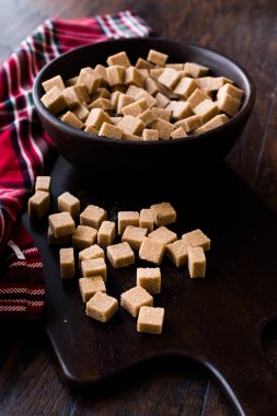 Ham organik kahverengi şeker küpleri içinde ahşap kase yemeye hazır. Gıda ürünleri.