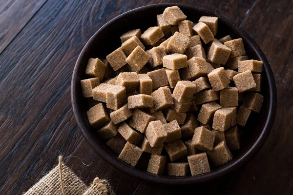 Ham organik kahverengi şeker küpleri içinde ahşap kase yemeye hazır. Gıda ürünleri.