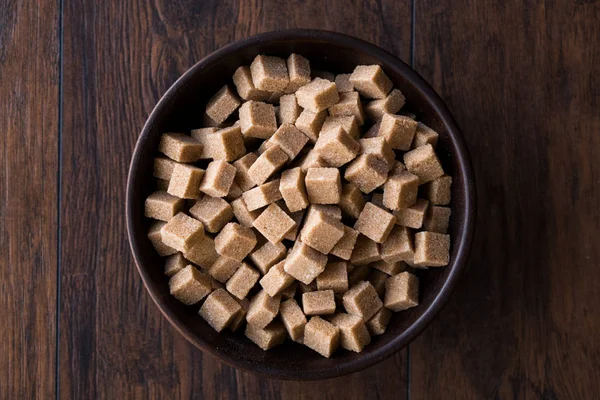 Ham organik kahverengi şeker küpleri içinde ahşap kase yemeye hazır. Gıda ürünleri.