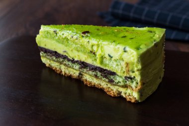 Matcha yeşil çay katman pasta dilimi koyu ahşap tahta üzerinde. Organik tatlı.