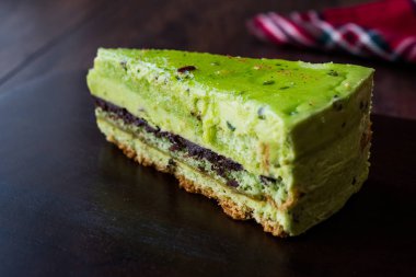Matcha yeşil çay katman pasta dilimi koyu ahşap tahta üzerinde. Organik tatlı.