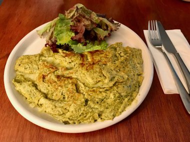 Yeşil omlet Pesto sos ve salata ile Restaurant, hizmet. Kahvaltı için organik gıda.