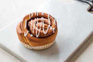 Ev yapımı taze tarçın rulo / topuz krema sosu ile servis mermer kurulu ile. Organik tatlı.