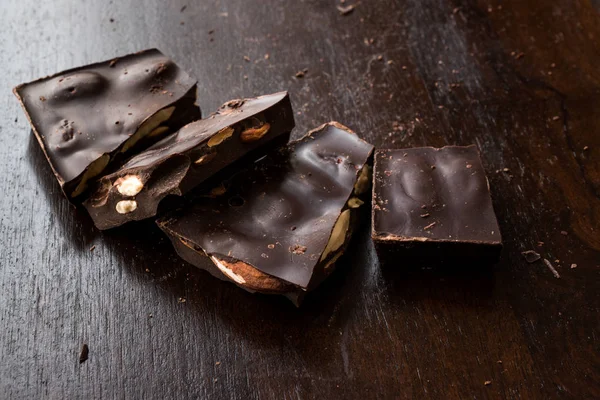 Koyu ahşap yüzey üzerinde acı badem çikolata parçaları. Organik aperatifler.