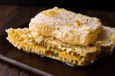 Koyu ahşap tahta üzerinde bal ile taze petek dilimleri. Organik gıda.