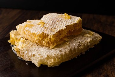 Koyu ahşap tahta üzerinde bal ile taze petek dilimleri. Organik gıda.