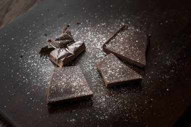 Acı çikolata parçaları ile deniz tuzu koyu ahşap yüzey üzerinde.