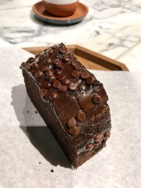 Mermer yüzeyinde kahve ile çikolata yongası sünger kek Slice.