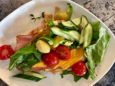 Pastırmalı Kruvasan Sandviç ve Çedar Peynirli Salata, Yeşil Zeytin, Salatalık ve Çeri Domates ile servis edilir