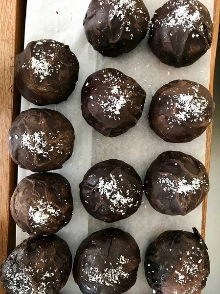 Bolas de trufa de chocolate con polvo de coco en papel con bandeja de madera . — Foto de Stock