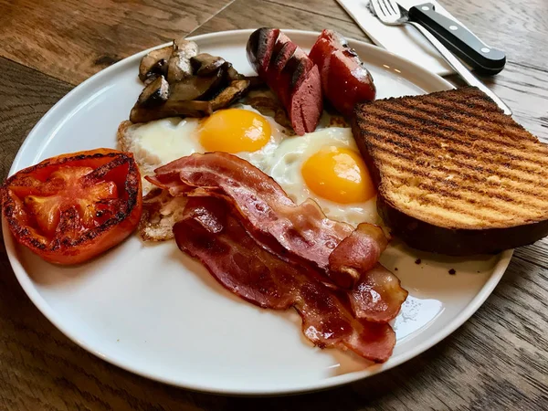 Aussie / Australian Café da manhã com brinde Brioche, ovos fritos, salsicha de bacon crocante, panquecas salgadas e cogumelos . — Fotografia de Stock