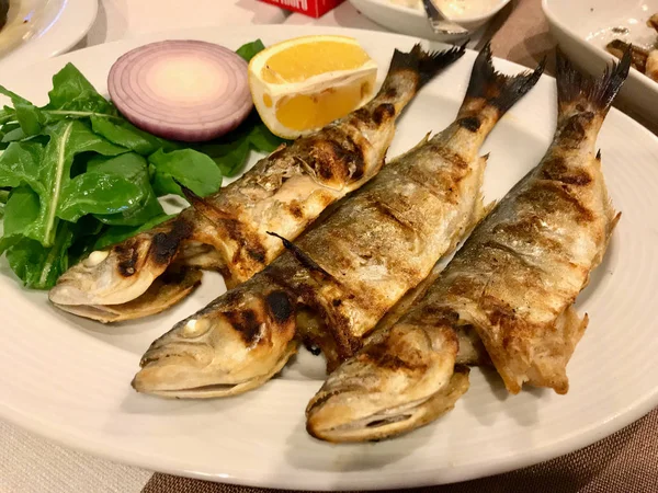 Kinesisk fisk Cinekop/Sarikanat bluefish på restaurang serveras med lök och sallad från Istanbul Turkiet. — Stockfoto