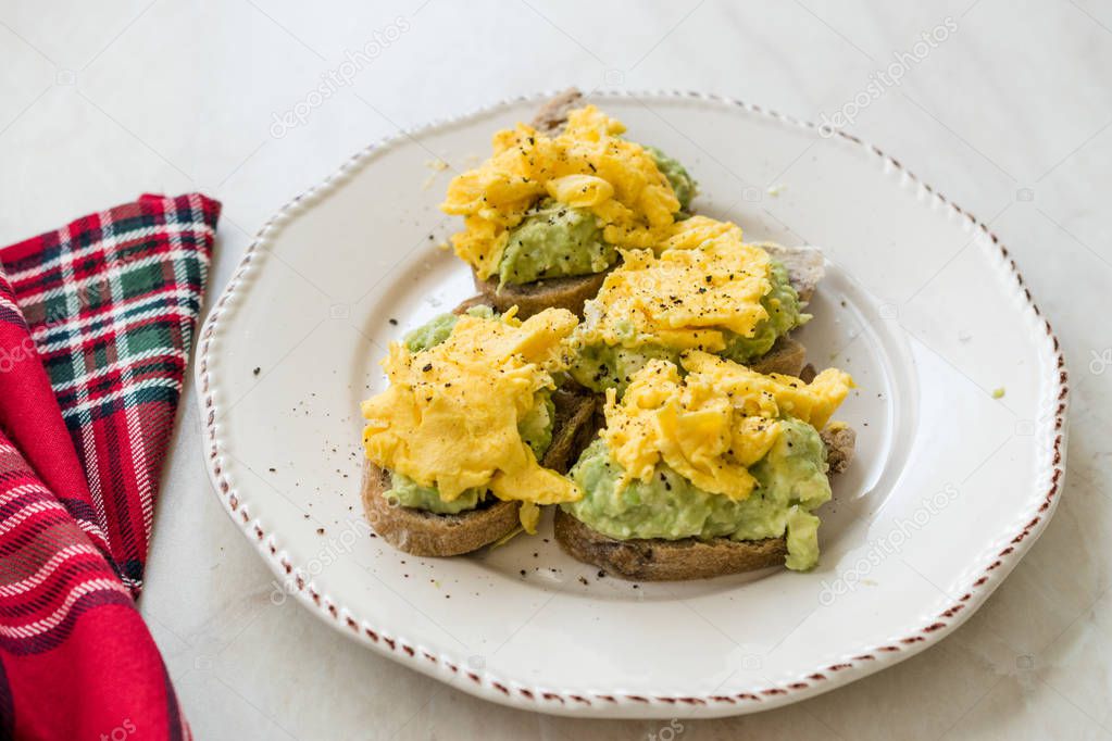 Scrambled Eggs with Avocado on Toast Bread for Breakfast.