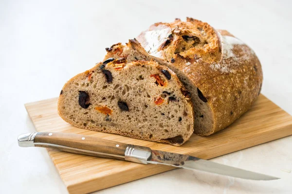 Handwerkliches Bäckerbrot mit getrockneten Tomaten und schwarzen Oliven fertig zum Essen. — Stockfoto