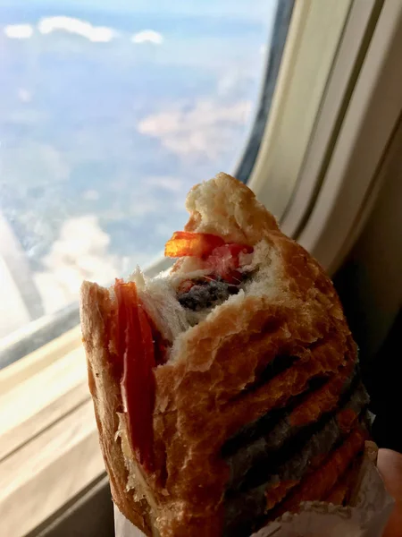 Сендвіч в літаковій кабіні економ класу тримається з рукою поруч з видом на вікно . — стокове фото