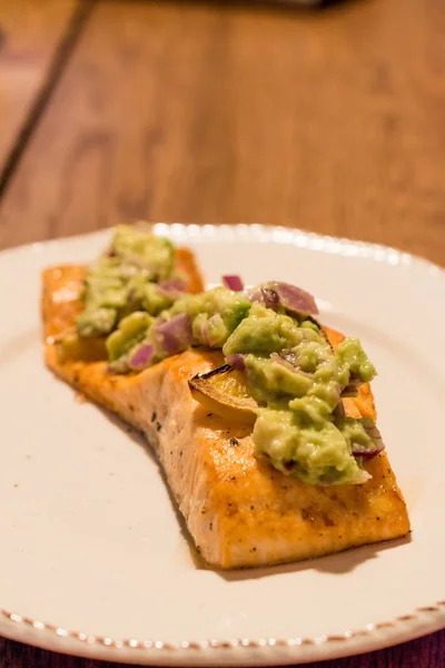 Filé de salmão com abacate em prato na mesa de jantar . — Fotografia de Stock