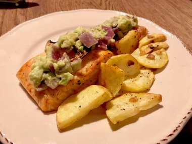 Yemek masasında plakalı avokado ile somon fileto.