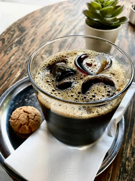 Café Cold Brew con hielo en la cafetería servido con galletas en la mesa de madera . — Foto de Stock