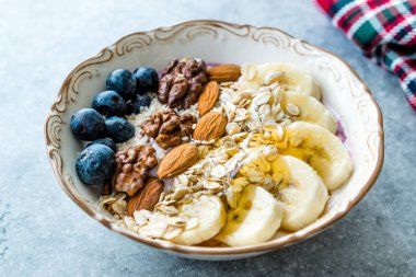 Yoğurt, Böğürtlen, Muz Dilimleri, Ceviz, Bal, Reçel, Yulaf, Badem, Susam ve Porselen Kase granola ile Acai Bowl.