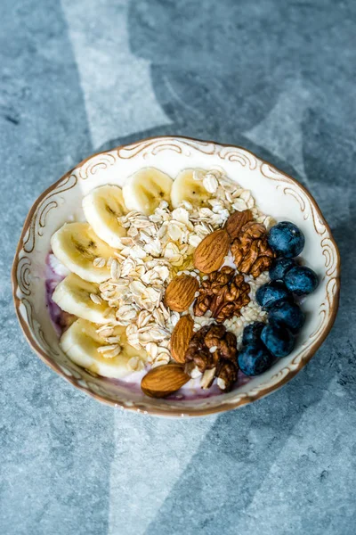 Yoğurt, Böğürtlen, Muz Dilimleri, Ceviz, Bal, Reçel, Yulaf, Badem, Susam ve Porselen Kase granola ile Acai Bowl.