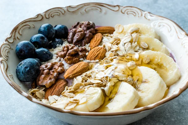 Acai Bowl with Yogurt, Blackberry, Banana Slices, Walnut, Honey, Jam, Oat, Almond, Sesame Seeds and Granola in Porcelain Bowl. — Stock Photo, Image