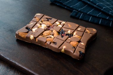 Ahşap Tahta üzerinde Badem, Fındık ve Kuru Üzüm bluberry Sütlü Çikolata Bar.