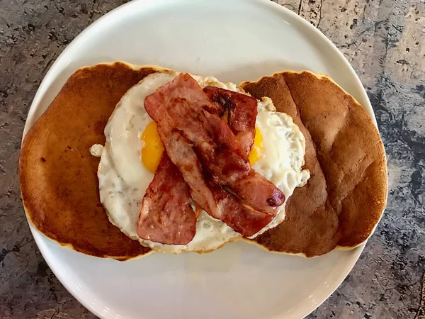 Gezouten pannenkoek met eieren en knapperig spek voor een hartig ontbijt geserveerd met koffie. — Stockfoto