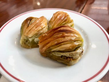 Yeşil fıstık tozu ve tereyağı kremi ile Türk midye baklava (Mussel şekli Baklawa). 
