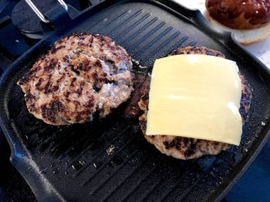 Grill üzerinde Cheddar peynir ile ızgara Hamburger Patty. Hizmete hazır.