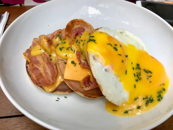 Panqueques salados con salsa holandesa, queso cheddar derretido, huevos y tocino crujiente para el desayuno . — Foto de Stock