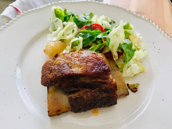 Мясо из телячьих ребер с салатом подается в тарелке . — стоковое фото