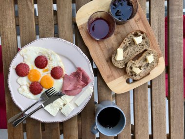 Kızarmış Yumurtalı Türk Kahvaltısı Sucuk, Eritilmiş Peynir, Tereyağlı Ekmek ve Reçel / Marmelat Taze Filtre Kahve ile servis edilir.