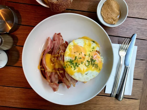 Panqueques salados con salsa holandesa, queso cheddar derretido, huevos y tocino crujiente para el desayuno con café . —  Fotos de Stock