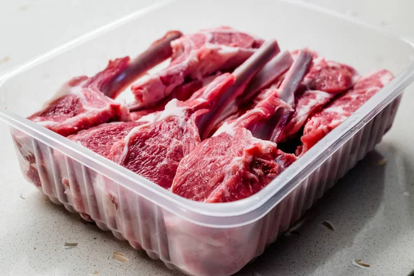 플라스틱 패키지 / 상자 또는 용기에 생 피 묻은 양갈비 고기 — 스톡 사진