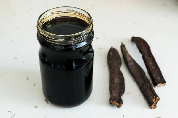 Carob Molasses in Jar with Pods Space . — стоковое фото