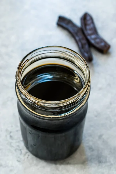 Carob Molasses in Jar with Pods Space . — стоковое фото