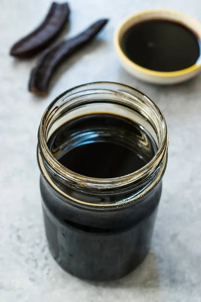 Carob Molasses in Jar with Pods Space . — стоковое фото