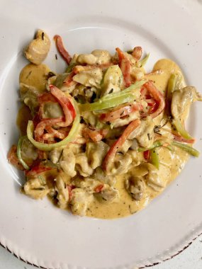 Kremalı körili tavuk, hardal ve tabak ile servis edilen Julienne sebzeleri..