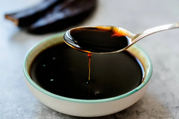 Carob Molasses Dripping from Spoon — Stock Photo, Image