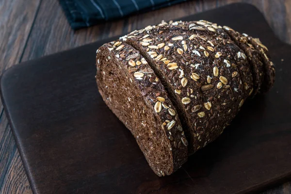 Malt Bread Slices with Oat and Flax Seeds on Dark Wooden Board.