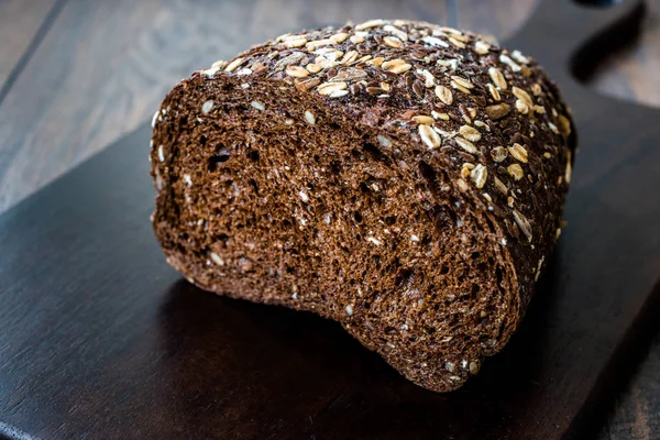 Malt Bread Slices with Oat and Flax Seeds on Dark Wooden Board.