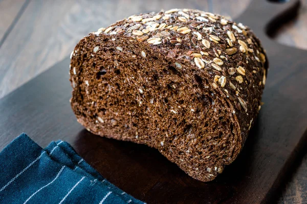 Malt Bread Slices with Oat and Flax Seeds on Dark Wooden Board.